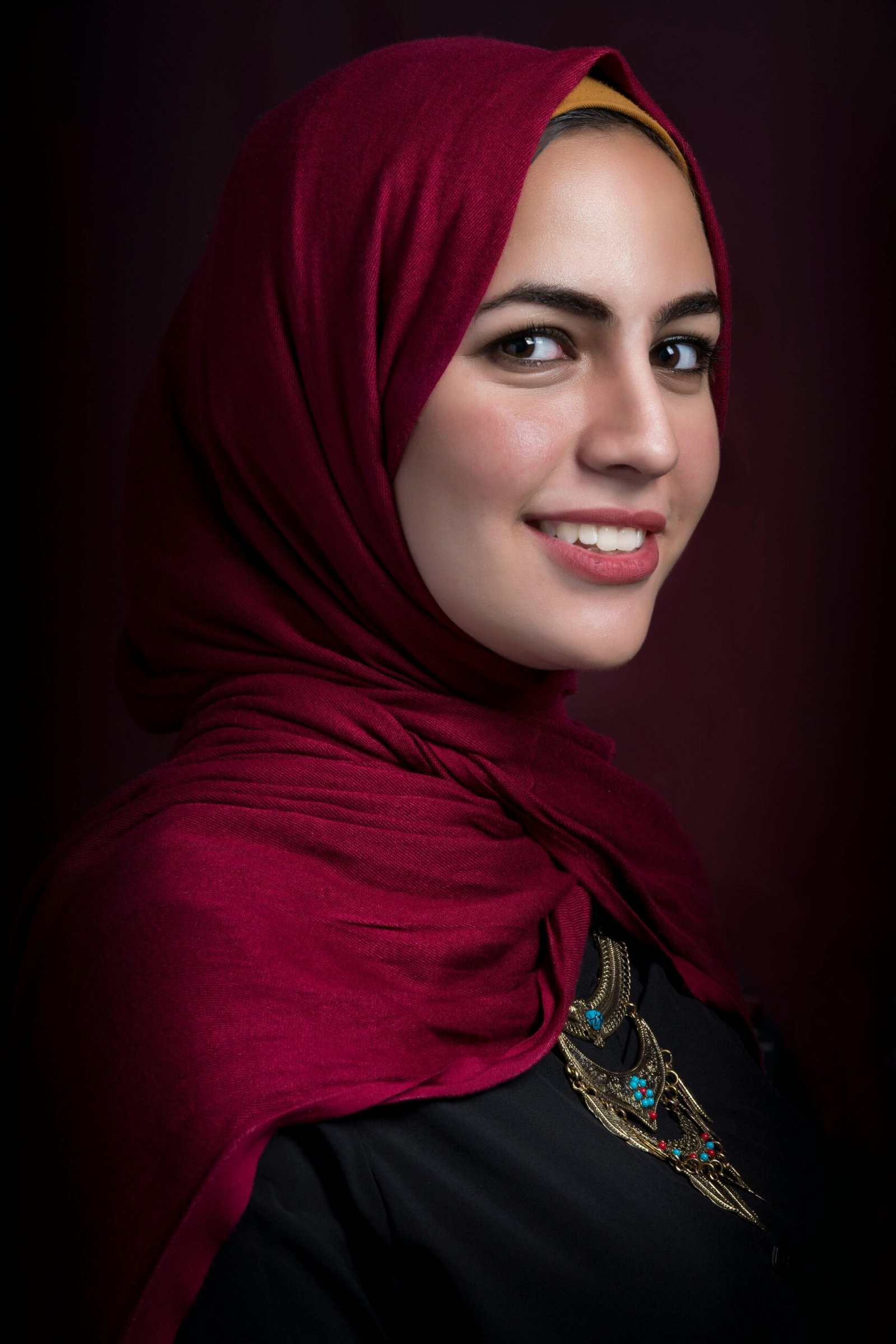 Stunning profile portrait of a woman wearing a red hijab, showcasing beauty and elegance.